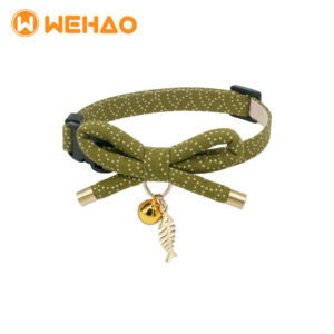Olive green polka dot cat collar featuring a bow tie, gold bell, and premium metal fishbone charm with a black breakaway safety buckle, branded with Wehao logo for B2B wholesale.