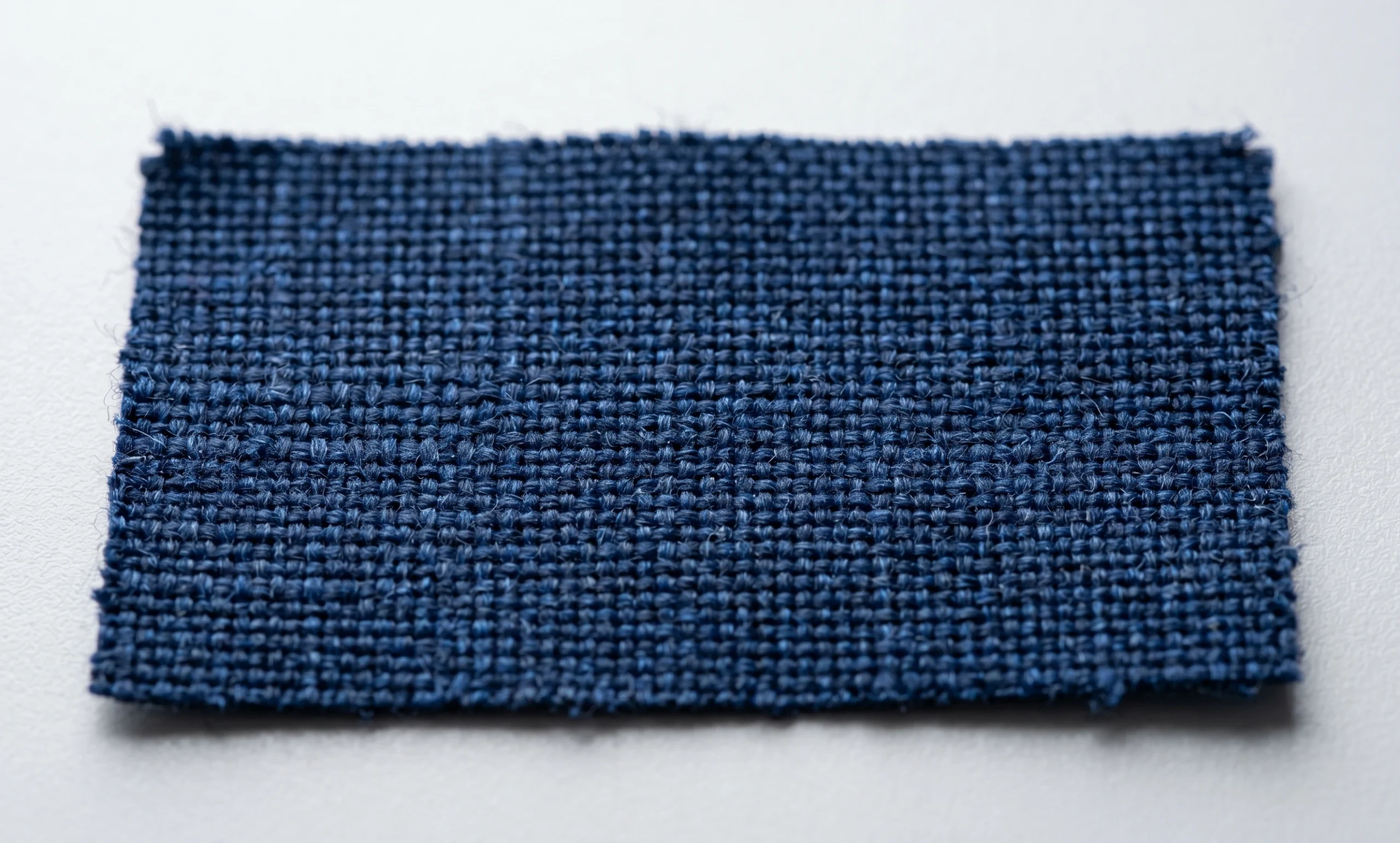 A detailed macro photograph showing the coarse weave and rugged texture of durable, navy blue heavy-duty Oxford cloth fabric used for tough pet products.