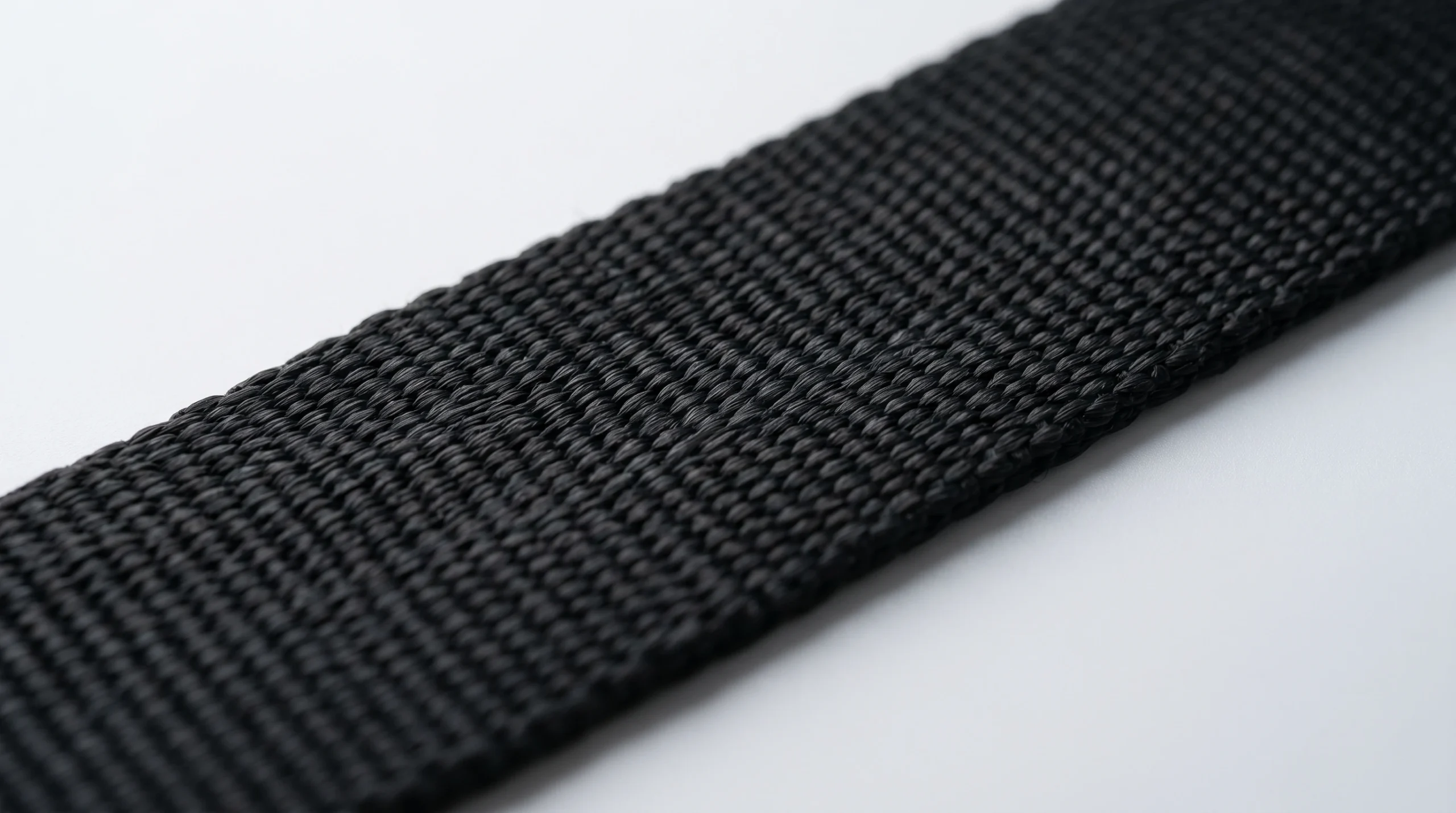 A macro photograph detailing the tight weave and durable texture of strong, black high-density nylon webbing used for pet leashes and harnesses.