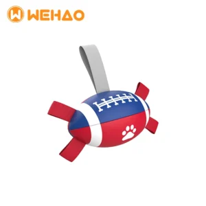 Red, white, and blue football shaped dog tug toy featuring a paw print, bone laces, and heavy-duty nylon straps for interactive fetch.