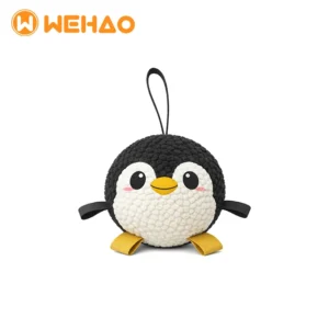 Round black and white plush penguin dog toy with textured bubble fabric, yellow nylon straps, and a top loop for interactive tugging.